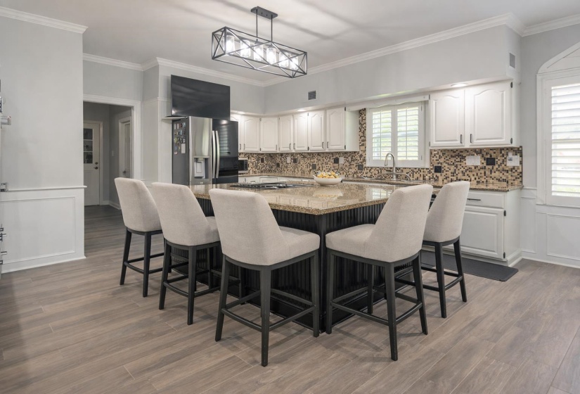 Two tone kitchen with a decorative wall, wainscoting, a center island, ornamental molding, and stainless steel refrigerator with ice dispenser