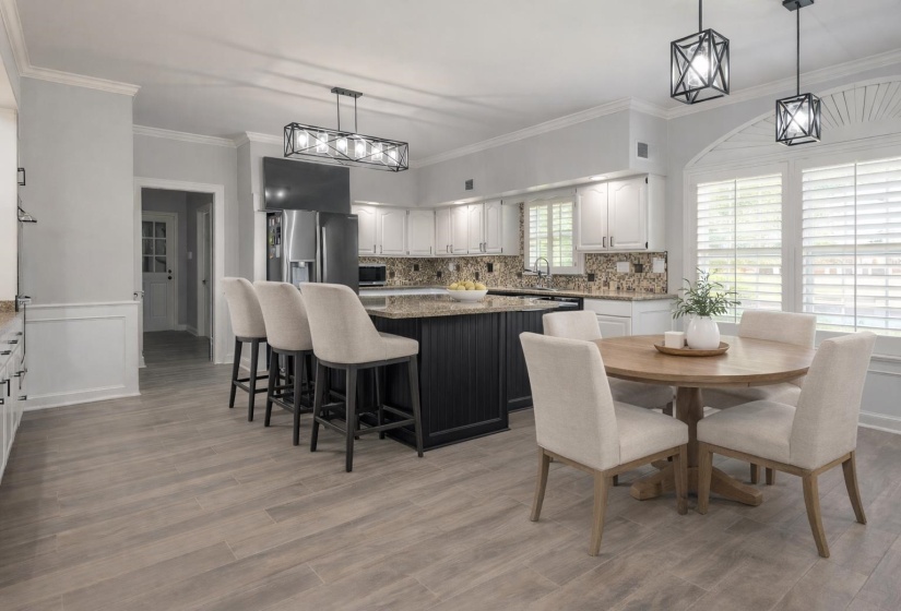 Dual tone kitchen featuring dark stone counters, a center island, ornamental molding, stainless steel appliances, and two tone cabinetry