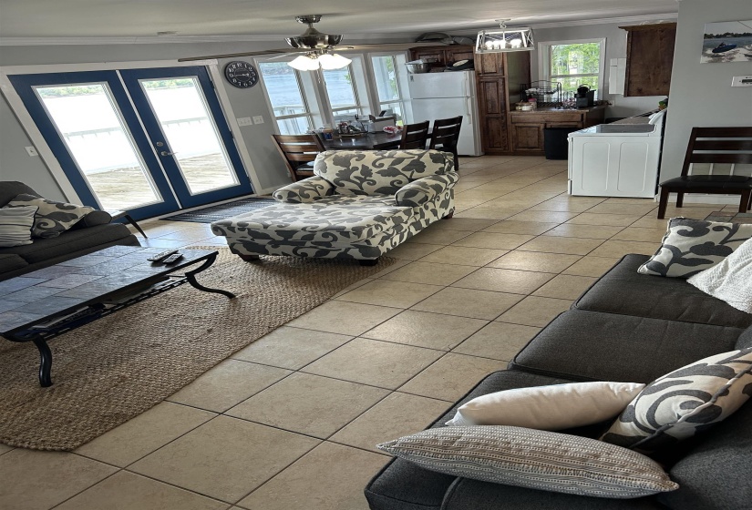 Living room with a ceiling fan, crown molding, french doors, and light tile patterned flooring Living room with a ceiling fan, crown molding, french doors, and light tile patterned flooring