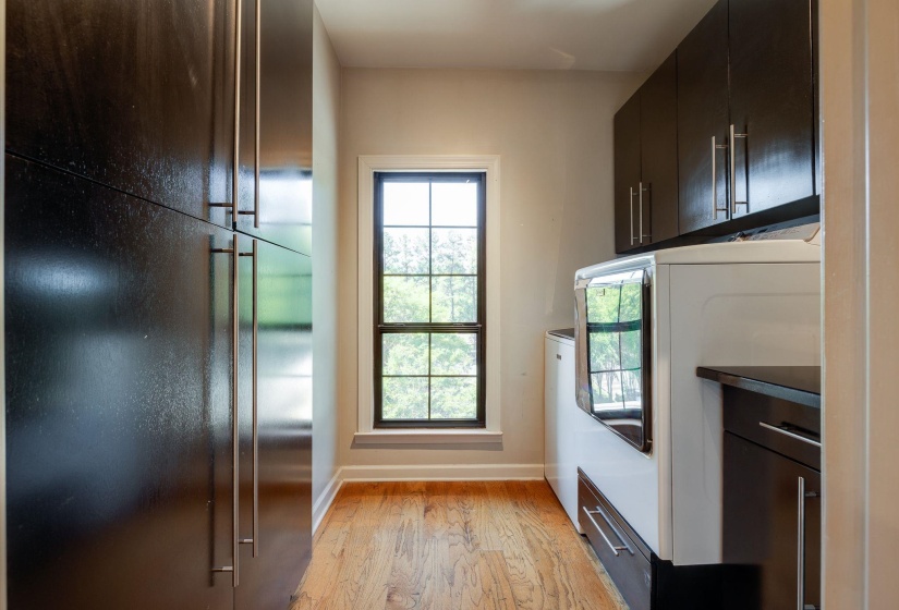 Laundry room with hardwood flooring and baseboards and levered doors