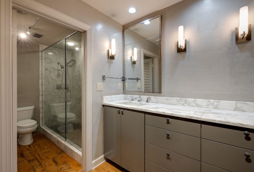 Bathroom featuring toilet, wood finished floors, a stall shower, and vanity
