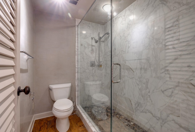 Full bathroom with toilet, a stall shower, a towel warming rack, and wood finished floors