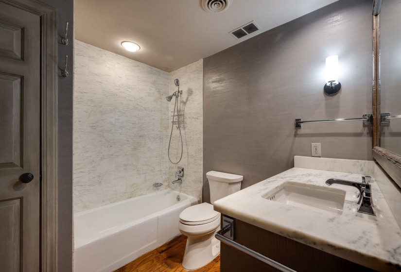 Bathroom with toilet, hardwood floors, shower / washtub combination, and vanity