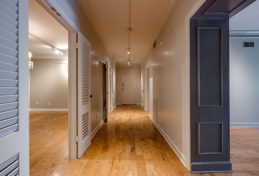 Corridor with light wood-style floors, crown molding, and baseboards