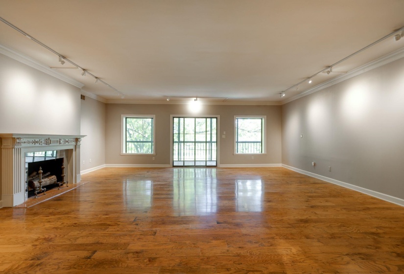 Unfurnished living room with track lighting, crown molding, healthy amount of natural light, wood finished floors, and a fireplace