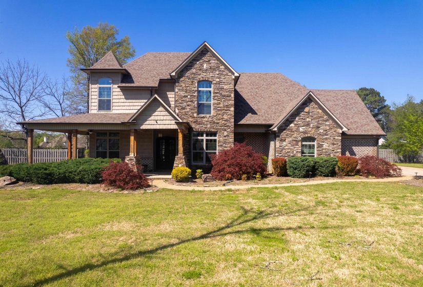 Craftsman-style home featuring a front yard, fence, a shingled roof, and stone siding