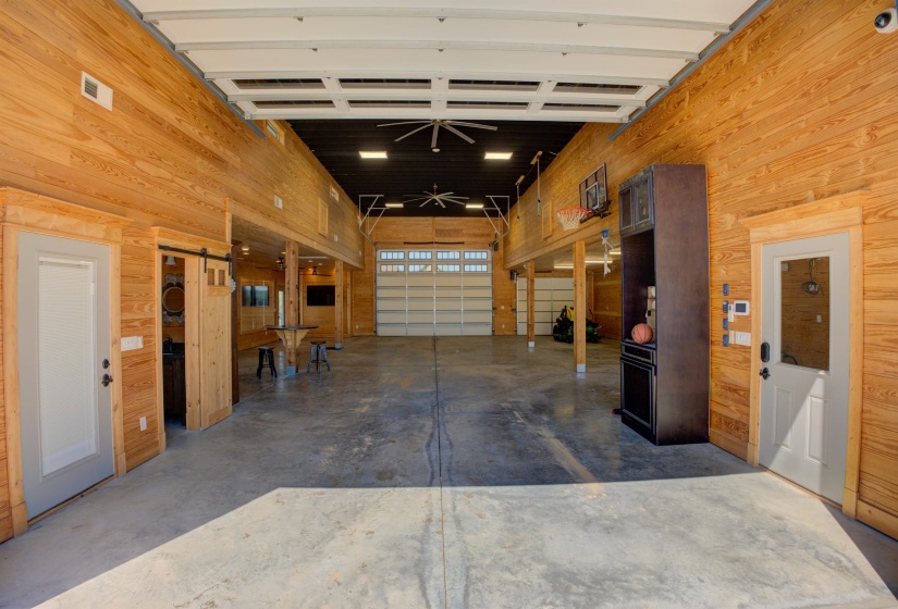 Garage with visible vents, a ceiling fan, and wooden walls