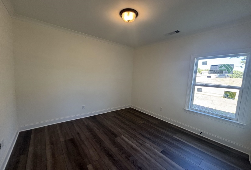 Spare room featuring crown molding and dark wood-type flooring