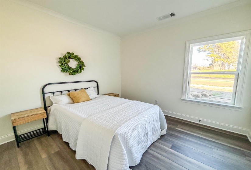 Bedroom with crown molding and dark wood-type flooring