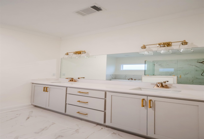 Full bathroom featuring double vanity, a marble finish shower, and light marble finish floors