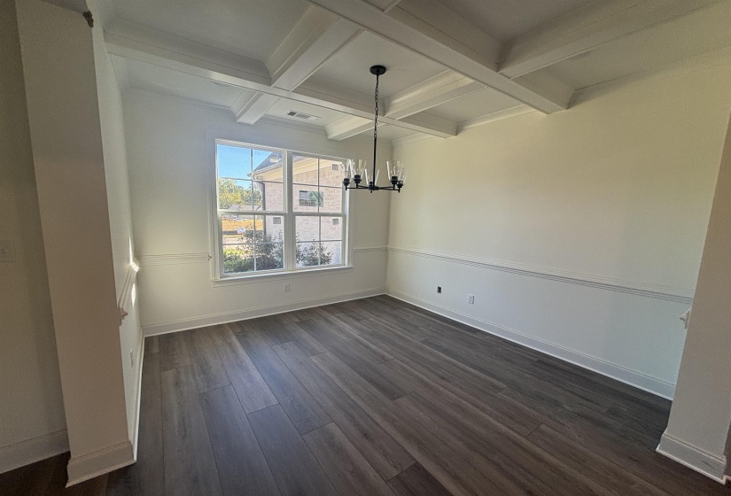 Unfurnished dining area featuring a chandelier, coffered ceiling, beam ceiling, and dark wood finished floors