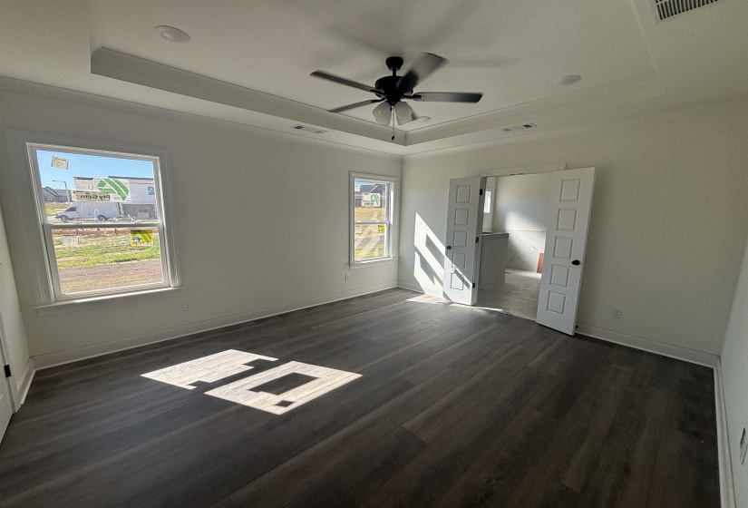 Empty room featuring a raised ceiling, dark wood-type flooring, and ceiling fan