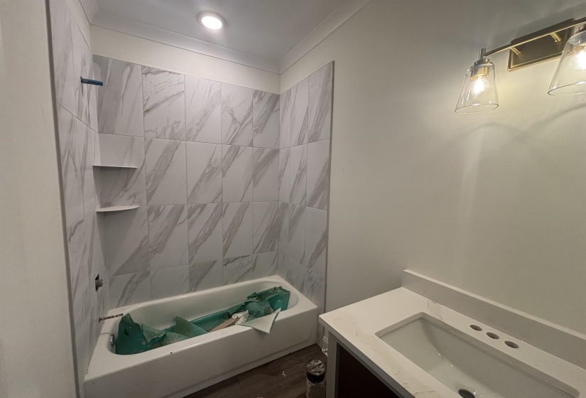 Full bath with washtub / shower combination, vanity, and dark wood-style floors