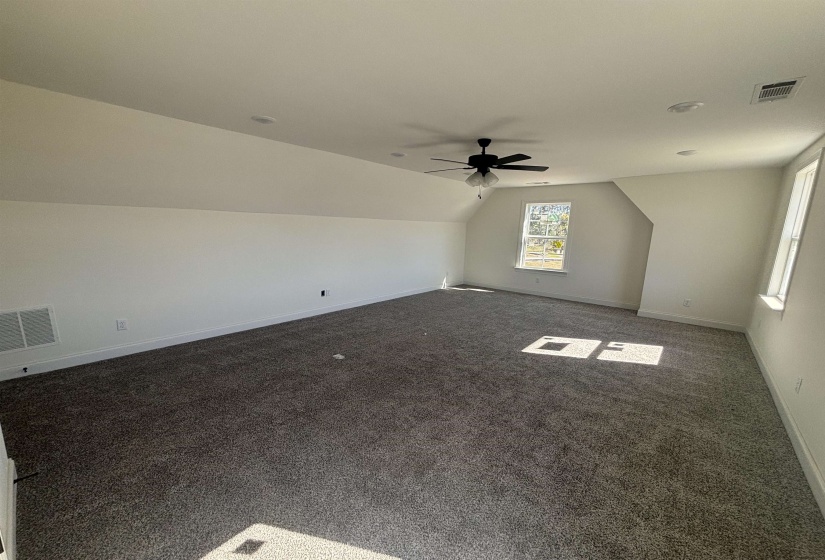 Additional living space with vaulted ceiling, dark carpet, and ceiling fan