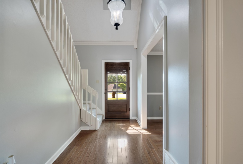 Entryway with stairs, dark wood-style flooring, baseboards, and ornamental molding