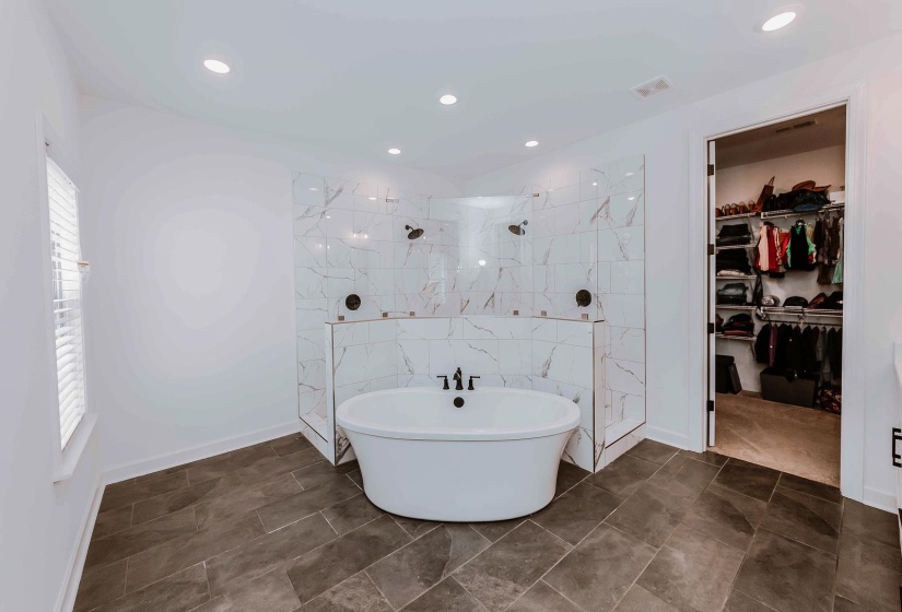 Bathroom featuring a walk in closet, a soaking tub, walk in shower, and visible vents