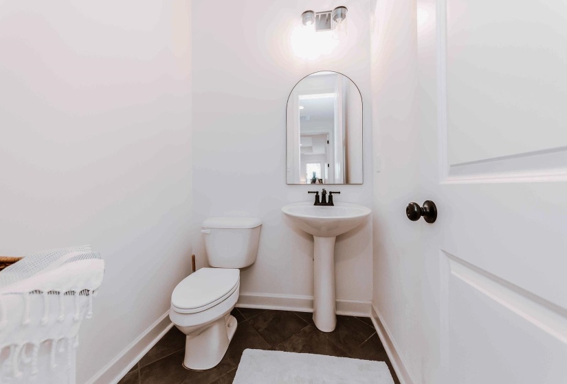 Half bathroom with baseboards, tile patterned flooring, and toilet