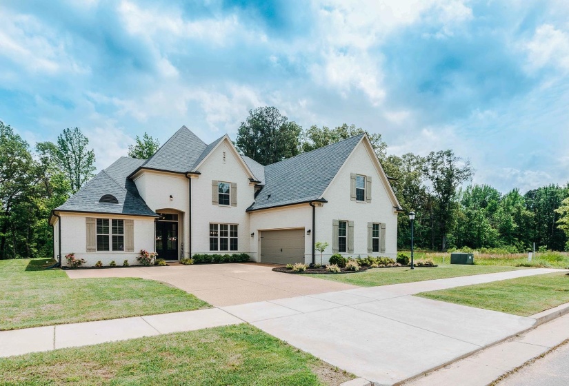 View of front facade featuring a front lawn, roof with shingles, and driveway