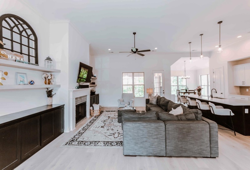 Living area featuring a fireplace, ceiling fan with notable chandelier, recessed lighting, and light wood-style flooring