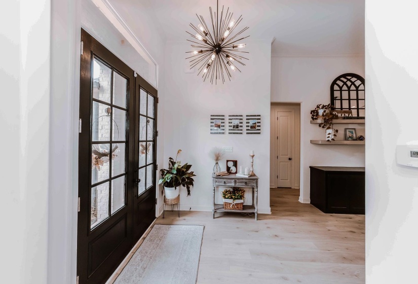 Entryway with french doors, crown molding, light wood-type flooring, baseboards, and a chandelier