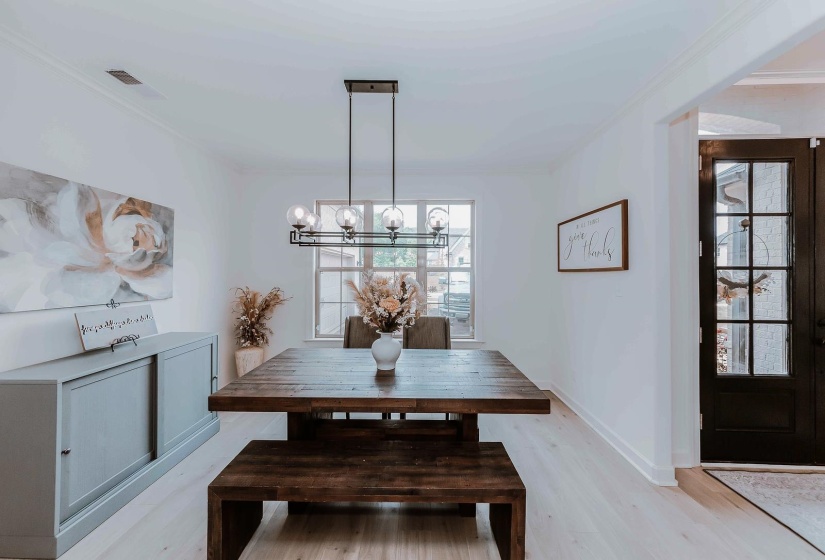 Dining space with an inviting chandelier, ornamental molding, visible vents, baseboards, and light wood-style flooring