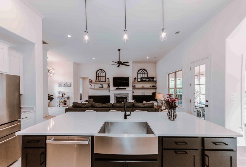 Kitchen with ceiling fan, a sink, light countertops, open floor plan, and stainless steel appliances