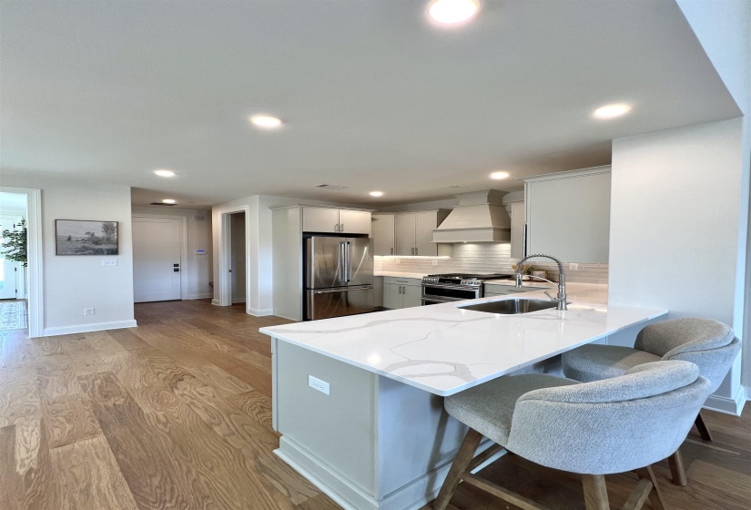 Kitchen featuring a kitchen breakfast bar, a peninsula, appliances with stainless steel finishes, decorative backsplash, and light stone counters