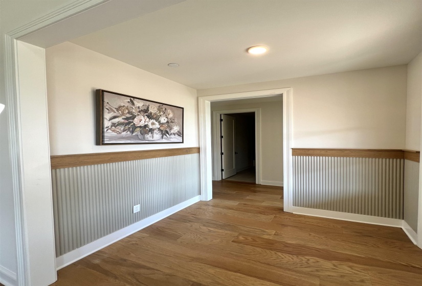 Corridor featuring light wood finished floors, a wainscoted wall, and recessed lighting