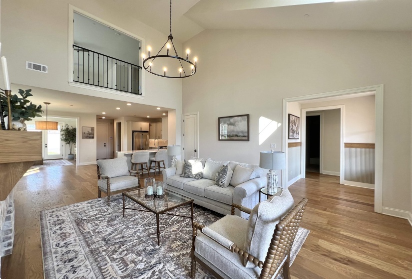 Living room with light wood-style floors, a chandelier, and high vaulted ceiling