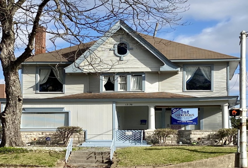 Exterior space featuring covered porch, a shingled roof, a chimney, and a front lawn