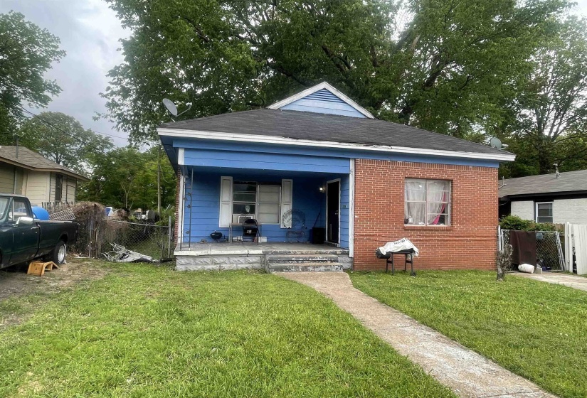 Rear view of house with fence, covered porch, a yard, and brick siding