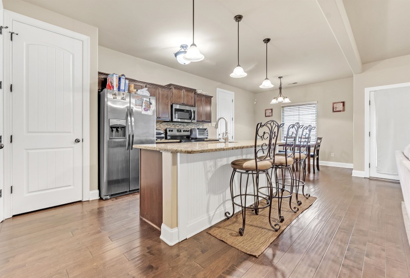 Kitchen featuring a breakfast bar area, an island with sink, a sink, stainless steel appliances, and light wood-style floors