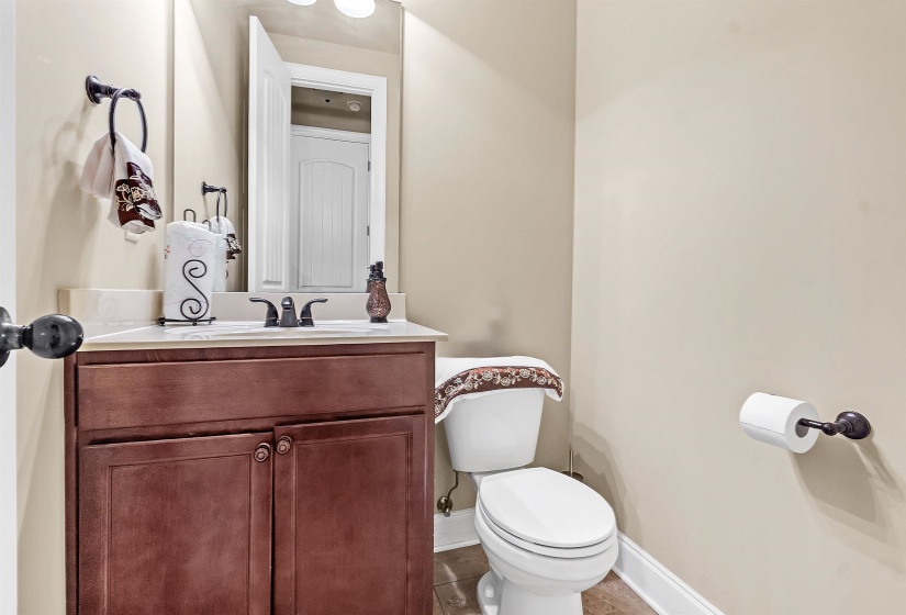 Half bathroom with toilet, baseboards, and vanity