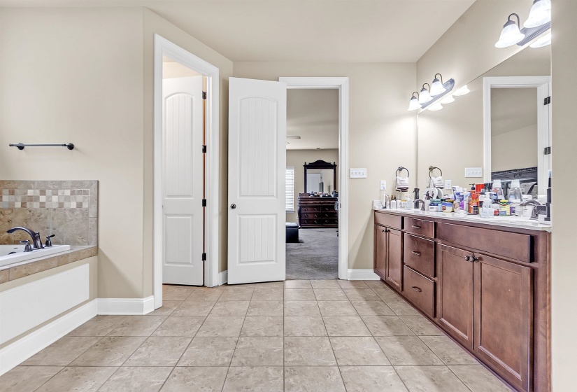 Full bath with baseboards, a sink, a bath, tile patterned floors, and double vanity