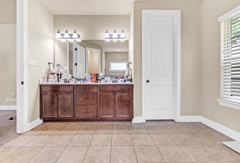 Full bath with baseboards, tile patterned flooring, double vanity, and a sink