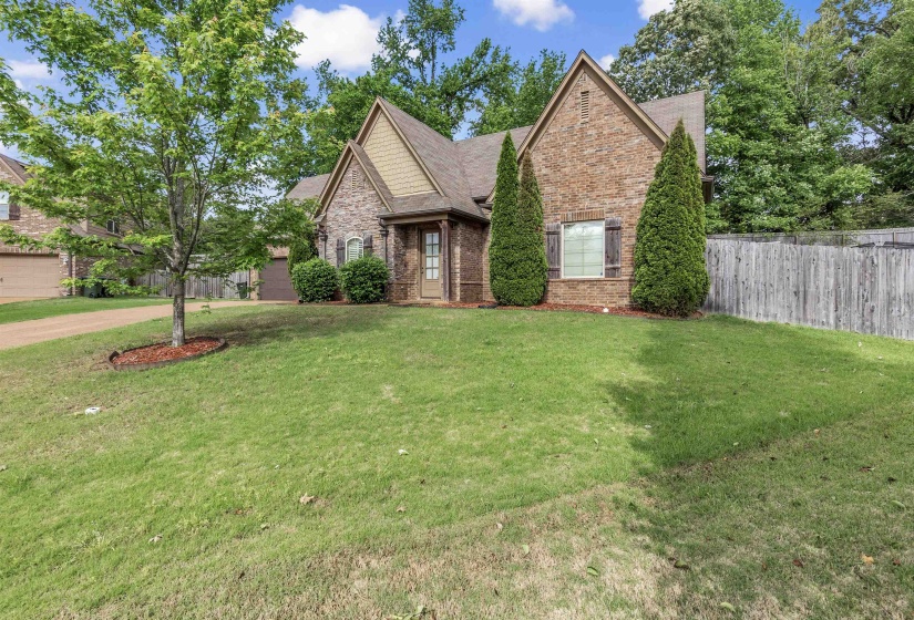 View of front of house featuring a front lawn, brick siding, roof with shingles, and fence