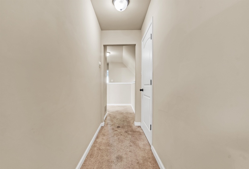Corridor with baseboards and light colored carpet