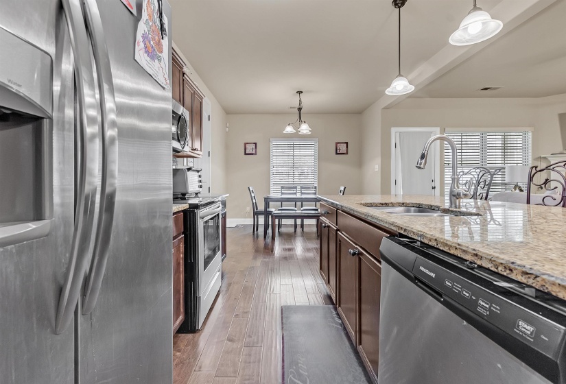 Kitchen featuring a sink, hardwood / wood-style flooring, an inviting chandelier, hanging light fixtures, and appliances with stainless steel finishes