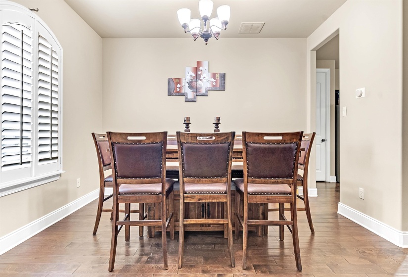Dining space with an inviting chandelier, visible vents, wood finished floors, and baseboards