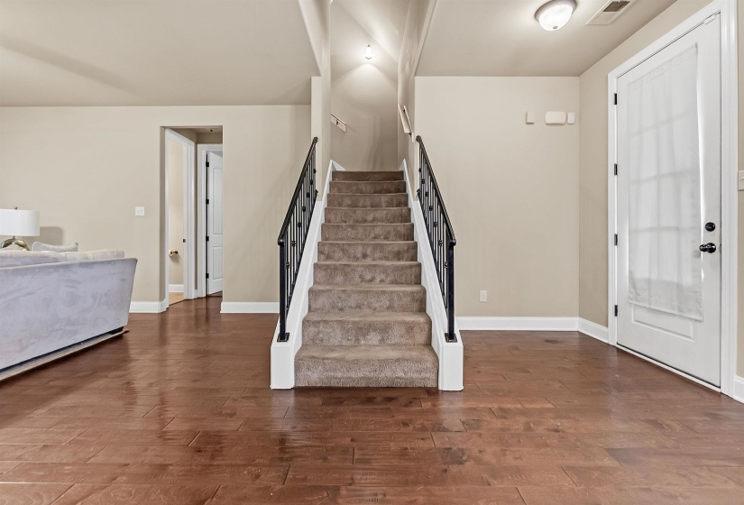 Foyer with visible vents, wood finished floors, baseboards, and stairway