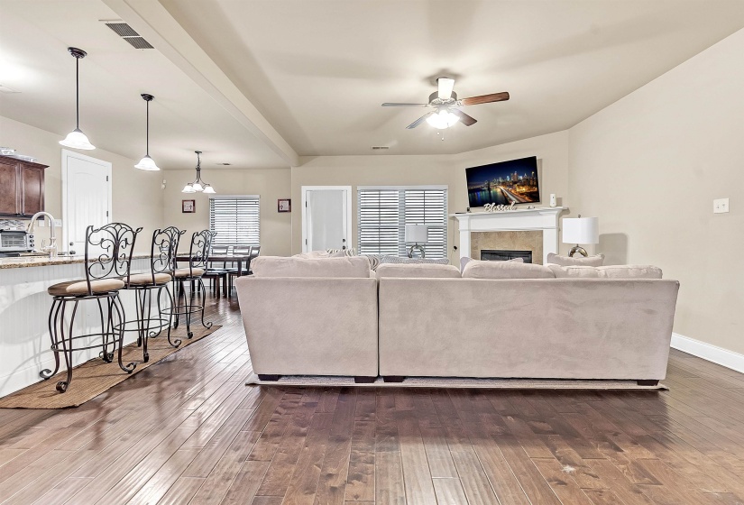 Living room with visible vents, a ceiling fan, dark wood-style floors, baseboards, and a tile fireplace