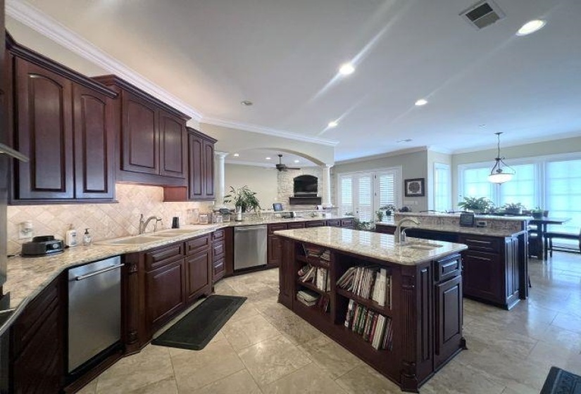 Kitchen featuring crown molding, dark brown cabinets, light stone countertops, a peninsula, and ceiling fan