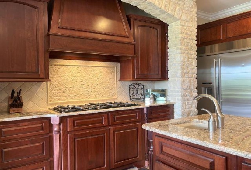Kitchen featuring built in fridge, gas stovetop, a sink, light stone countertops, and tasteful backsplash