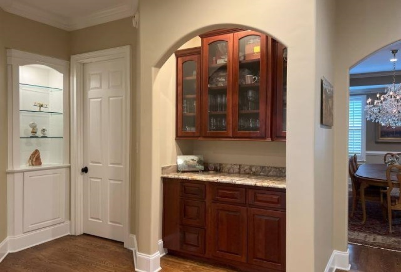 Bar featuring baseboards, an inviting chandelier, crown molding, and wood finished floors