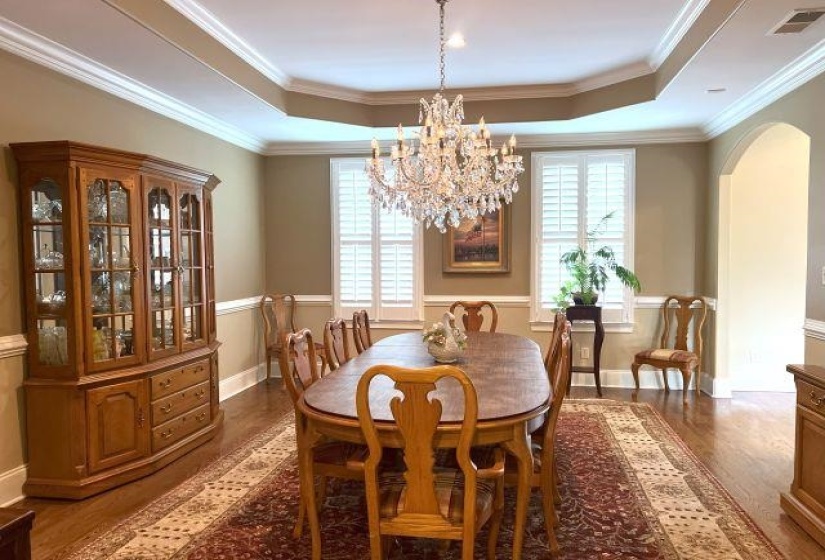 Dining room with a healthy amount of sunlight, a tray ceiling, visible vents, and dark wood-style floors