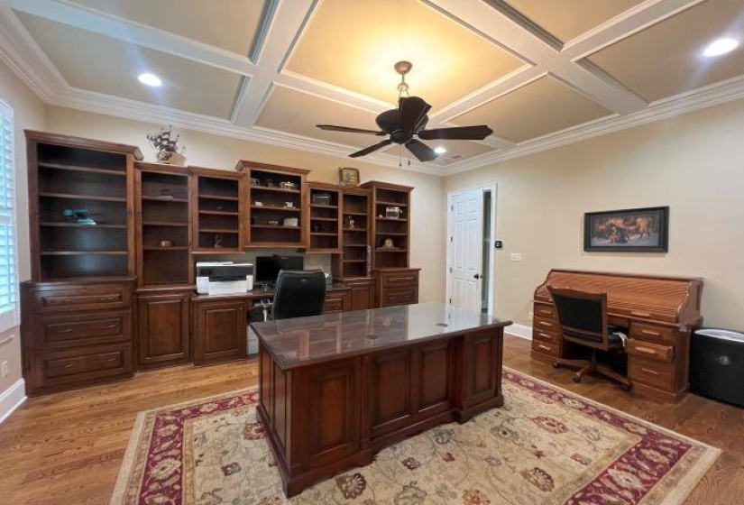 Office with coffered ceiling, light wood-style floors, a ceiling fan, and ornamental molding
