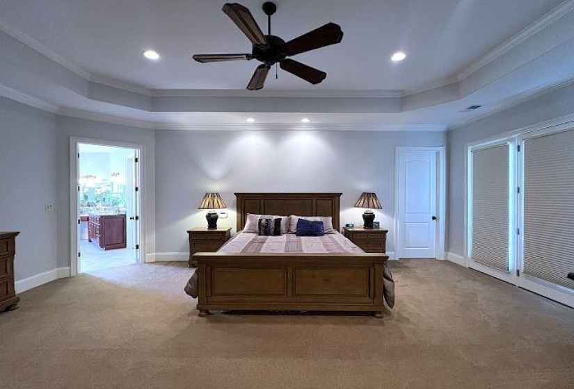 Bedroom with a raised ceiling, ornamental molding, carpet, recessed lighting, and ceiling fan