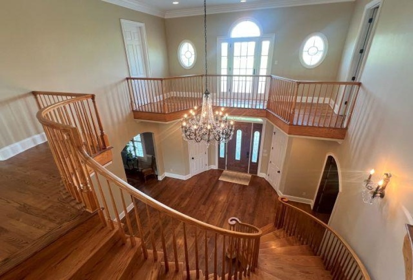 Entrance foyer with french doors, a wealth of natural light, an inviting chandelier, wood finished floors, and arched walkways