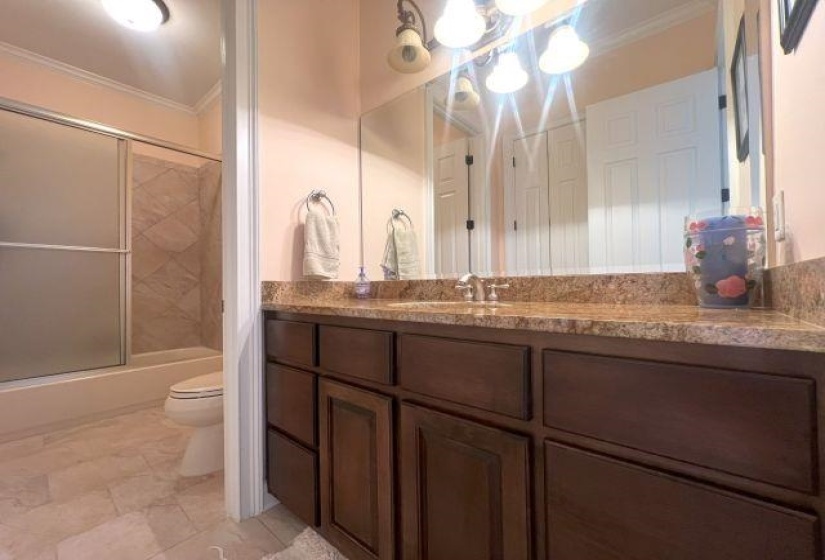 Bathroom featuring toilet, enclosed tub / shower combo, a chandelier, vanity, and ornamental molding