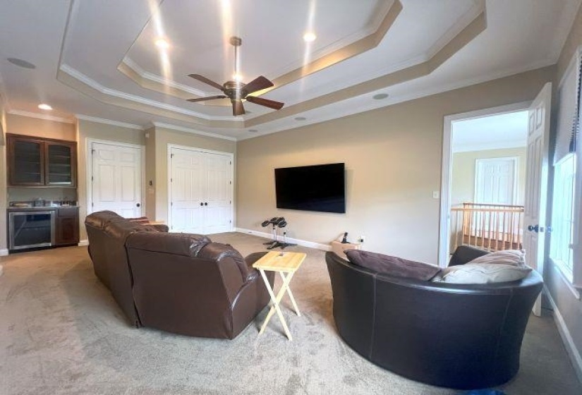 Living room featuring ceiling fan, a tray ceiling, crown molding, and light-colored carpet